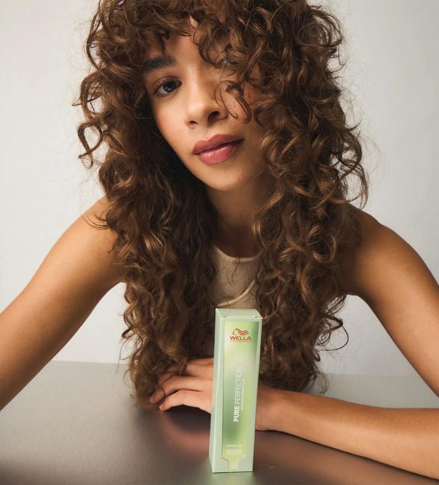 Modelka s dlhými kučeravými hnedými vlasmi pri balení Wella Professionals Pure Perfection