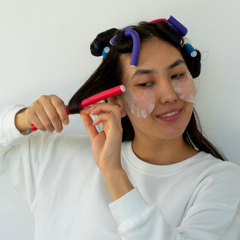 Žena si d&aacute;va n&aacute;tačky na vlasy pri dom&aacute;com stylingu vlasov